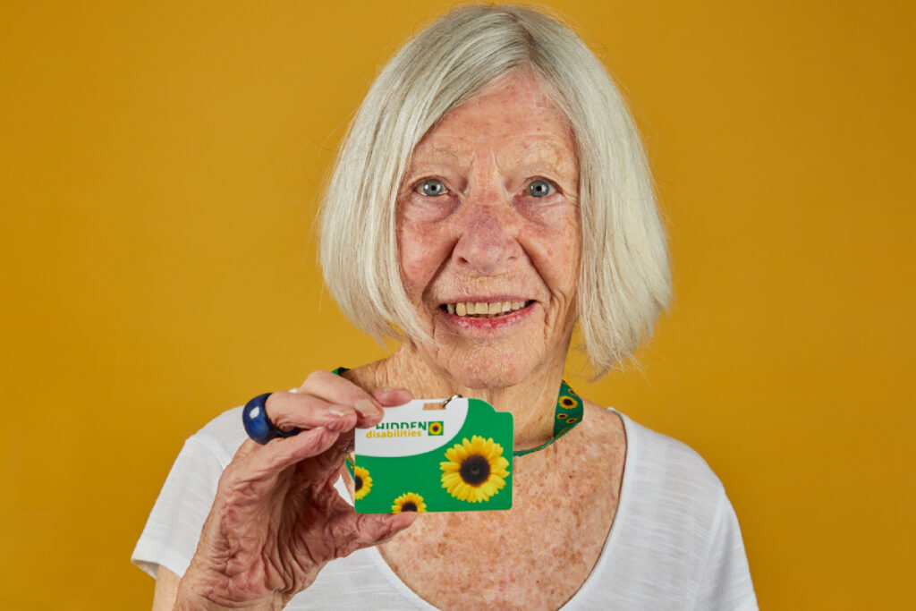 Hidden Disabilities Sunflower. Elderly lady holding a Sunflower lanyard with a card.