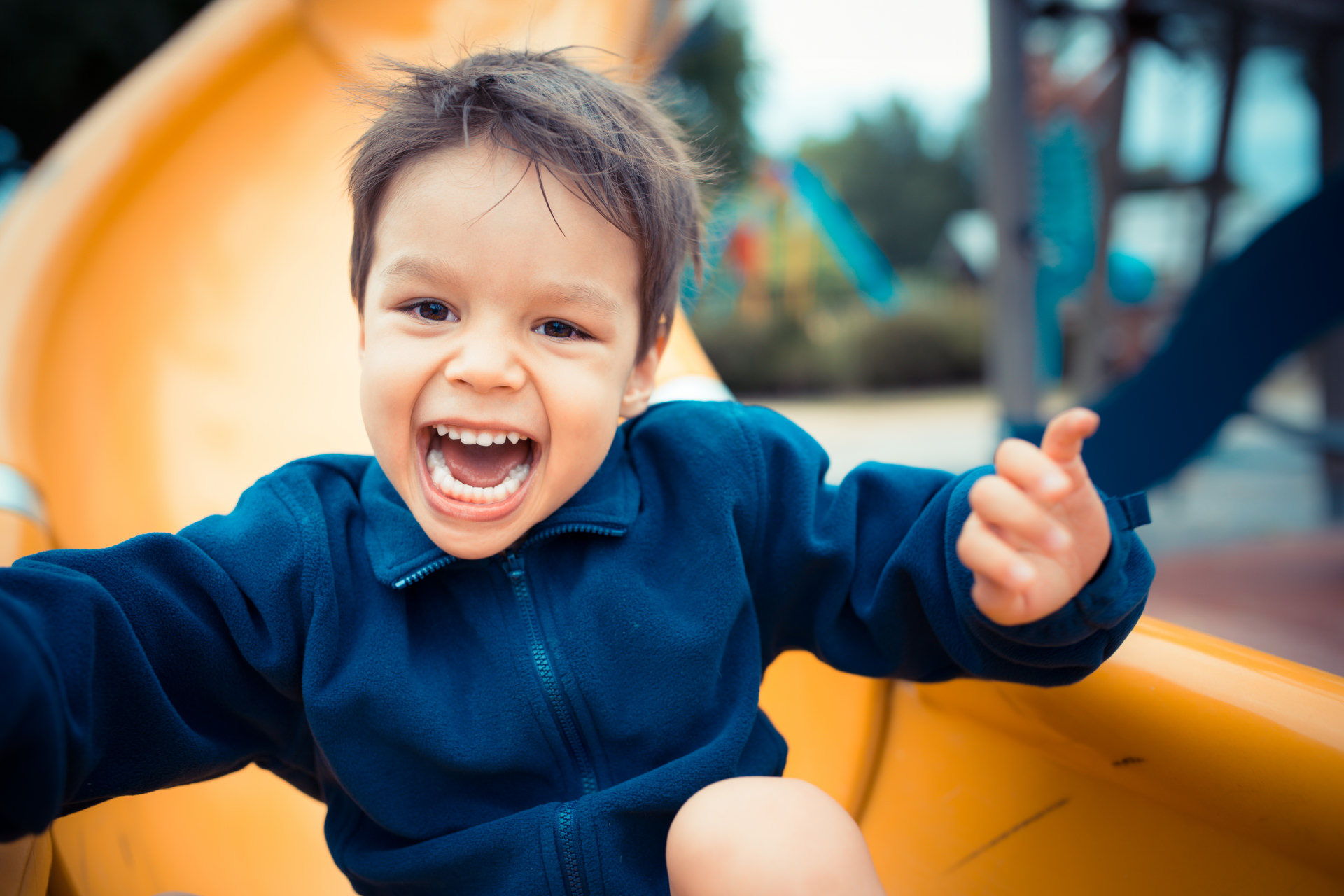 Young child happily playing on a slide.