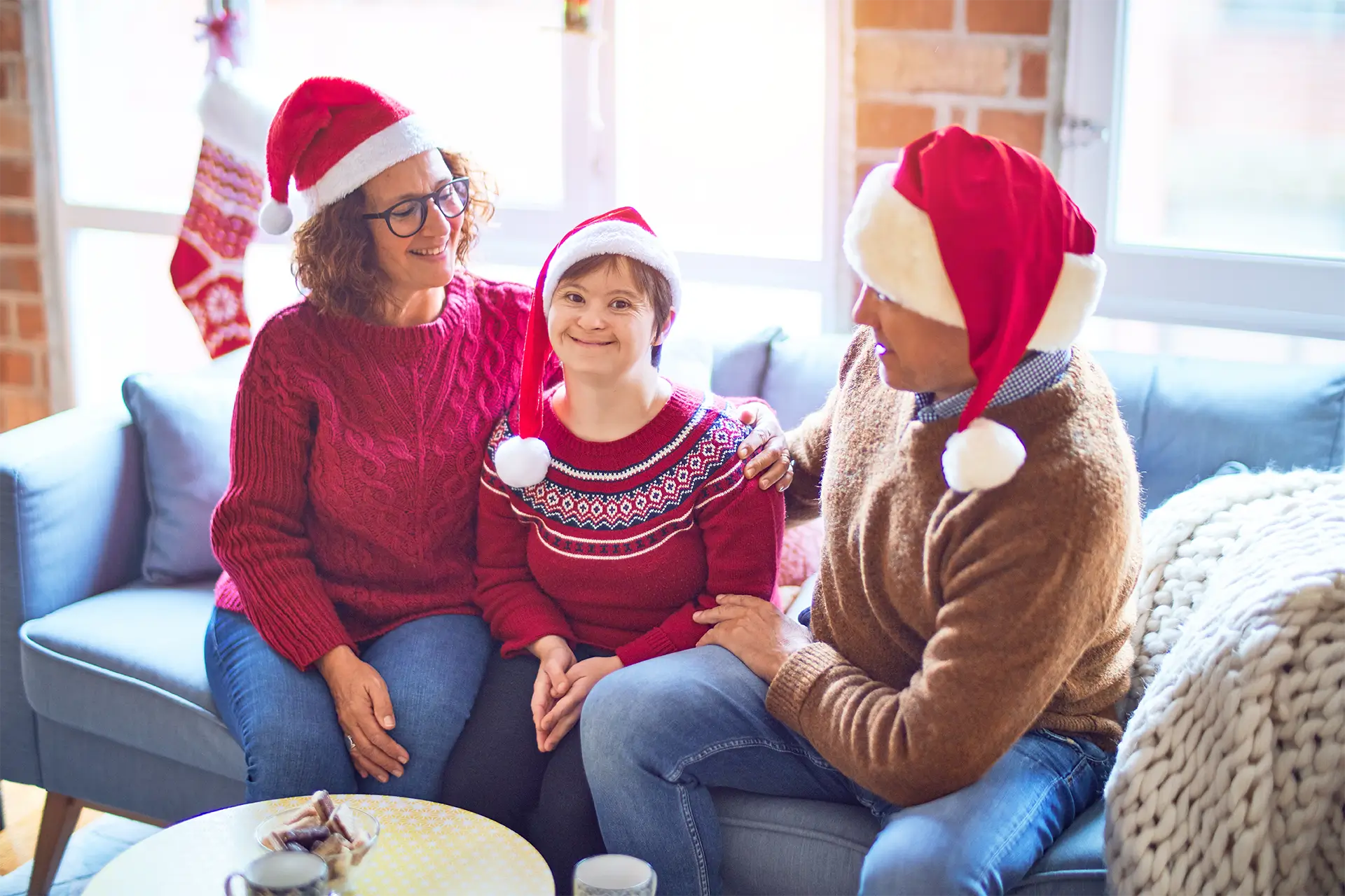 Three people sitting on a couch wearing Santa hats.
