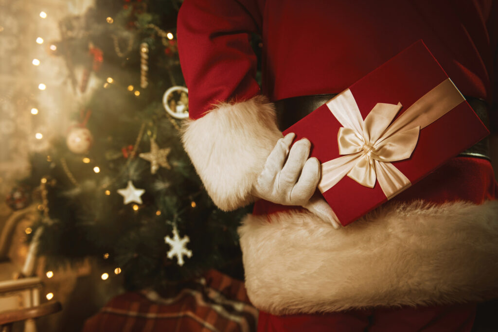 Santa holding a gift behind his back.