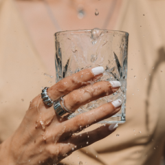Hand with jewellery holding a glass