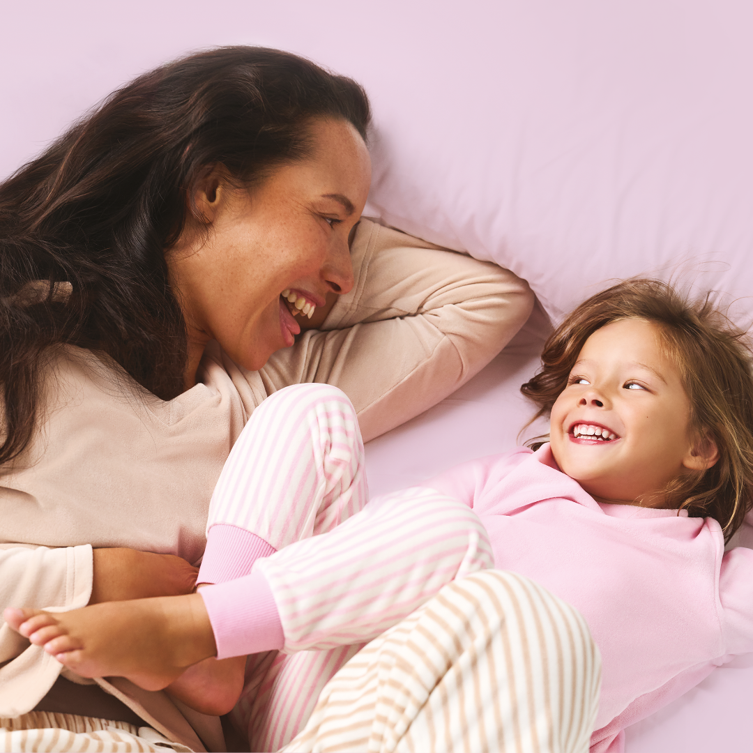 Mother and child lying on bed smiling