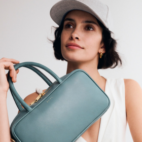 female wearing white cap and holding a aqua coloured bag