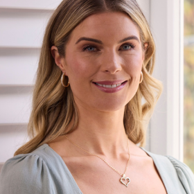 Woman with blonde hair wearing green dress and silver heart necklace