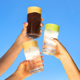 Three hands holding up three glasses of drinks