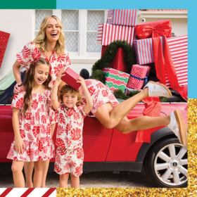 Family wearing matching outfits standing in front of red car, all smiling